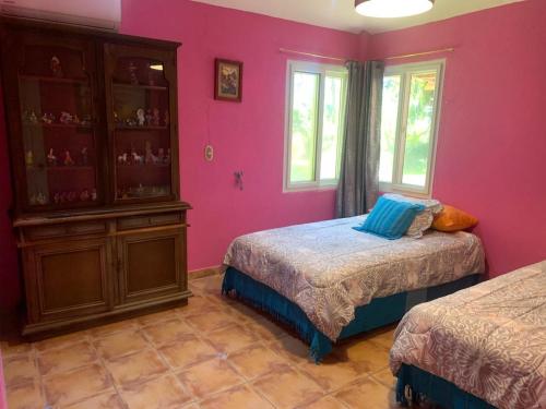 a pink bedroom with two beds and a cabinet at Rancho Colibrí in Acajutla