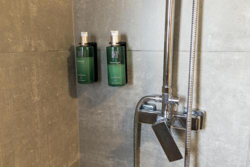 two green deodorant bottles on the wall of a shower at Bellu Suites by GuestPro in Guimarães
