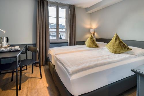 a hotel room with a bed and a desk and a window at Hotel Spinne Grindelwald in Grindelwald