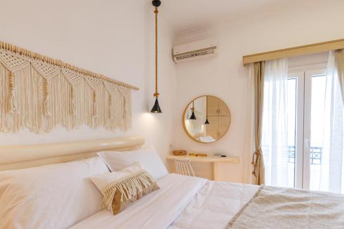 a white bedroom with a bed and a mirror at Golden Secret Beach House in Perissa