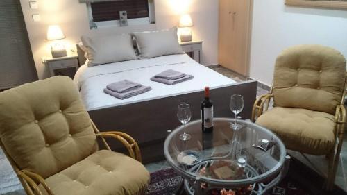 a bedroom with a bed and two chairs and a table at Studio Giannis, a breath away from Athens! in Neméa