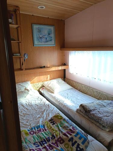 two beds in a small room with a window at Mobil home inter in Berck-sur-Mer