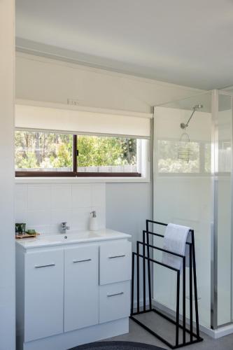 a white bathroom with a sink and a window at Secret Spot - Bruny Island in Lunawanna