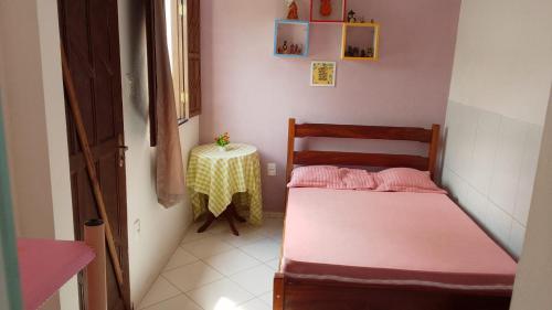 a small room with two beds and a table at Casa Rosa da Ilha - Suíte Confortável com Ventilador e Jardim in Vera Cruz de Itaparica