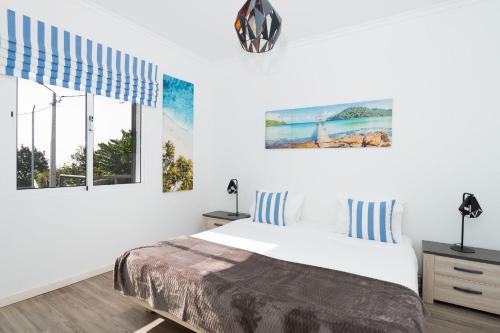 a white bedroom with a bed and two windows at Villa Liana by LovelyStay in Ponta do Sol