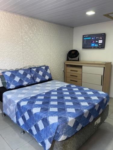 a bedroom with a blue and white bed and a dresser at Pousada aconchego in Imbituba