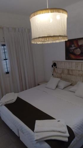 a bedroom with a large white bed with a chandelier at Alojamiento San Nicolas in La Rioja
