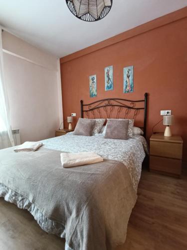 a bedroom with a large bed with orange walls at Piso Rualte in Ávila