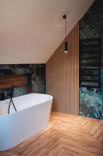a white bath tub in a room with wooden floors at Muciówka in Jurków