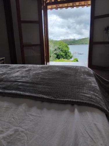 a bed in a room with a large window at rancho california rancho beira d'água Delfinopolis in Delfinópolis