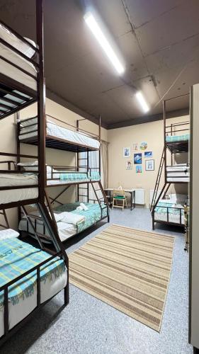 a room with three bunk beds and a rug at Sky Tau Hostel in Almaty