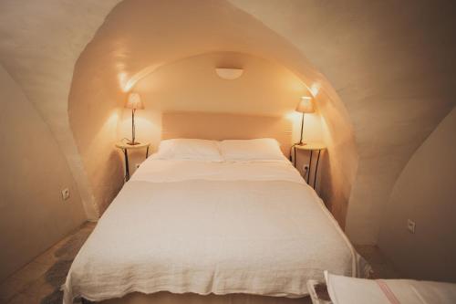 a white bed in a tunnel with two lamps at Ancienne Maison des Gardes in Lourmarin
