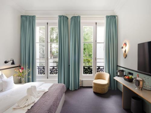 a bedroom with green curtains and a bed and a chair at Aussen Alster Hotel in Hamburg