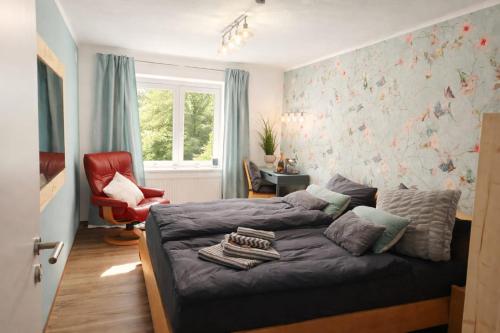 a bedroom with a bed and a red chair at Ferienwohnung Gartenglück im Mölltal in Semslach
