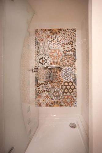 a bathroom with a mosaic tile wall and a shower at T3 Cosy - Art Déco in Villefranche-de-Rouergue