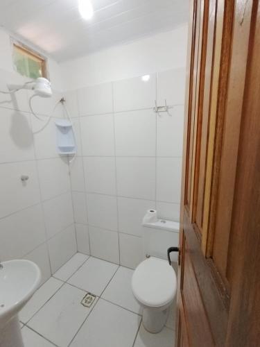 a white bathroom with a toilet and a sink at Pousada Kaa - Natureza e Sossego em Itacaré in Itacaré