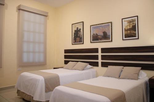 two beds in a hotel room with a window at Casa 3 Torres, Calle 76 in Mérida