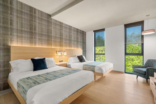 a hotel room with two beds and a chair at The Simon at Simon Fraser University in Burnaby
