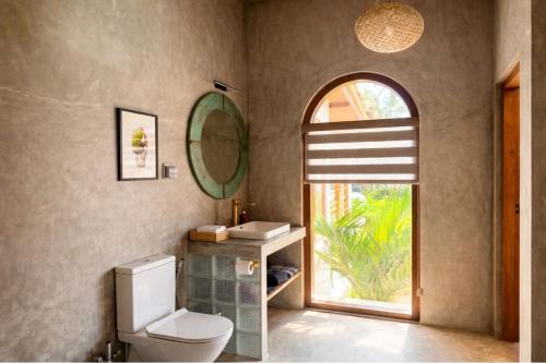 a bathroom with a toilet and a sink and a window at South Coast Villas by Mandala in Tangalle