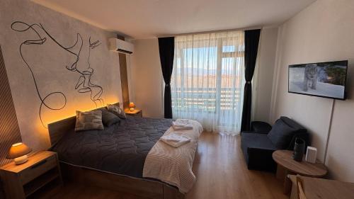 a bedroom with a bed and a chair and a window at Aspen Golf Resort Studio E206 in Bansko