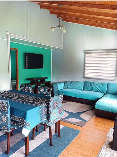 a living room with a blue couch and a tv at Cabañas "Parada Tentelhué" in Rolecha