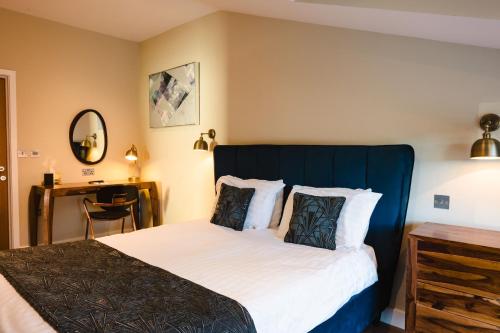 a bedroom with a large bed with a blue headboard at Crown Lodge Hotel in Wisbech