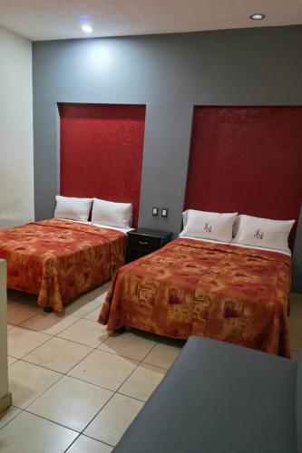 two beds in a hotel room with red headboards at J Alejandro - Centro Histórico Guadalajara in Guadalajara