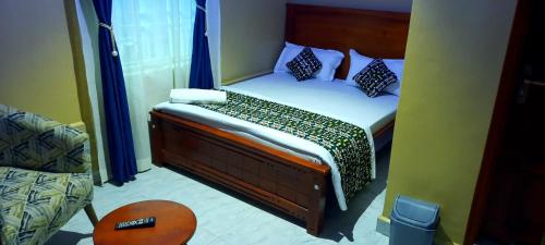 a small bedroom with a bed with blue curtains at Binyuma Suites Motel in Kampala