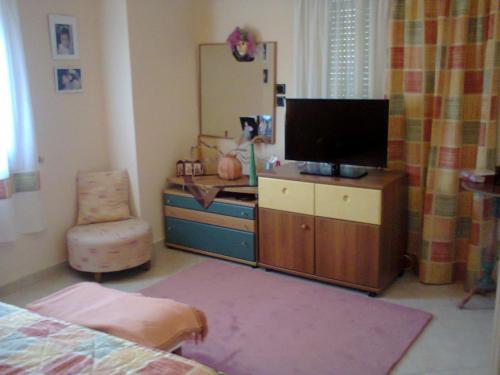 ein Schlafzimmer mit einem TV und einem Schreibtisch mit einem Stuhl in der Unterkunft Evgenia Apartment in Antikes Epidauros