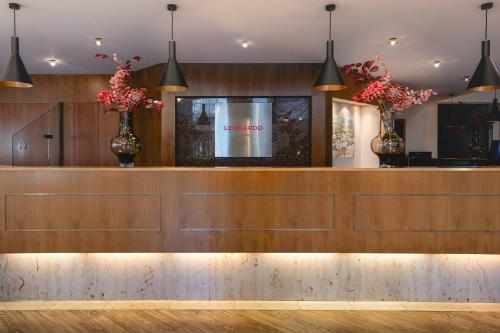 a restaurant with a counter with two vases with flowers at Leonardo Hotel Weimar in Weimar