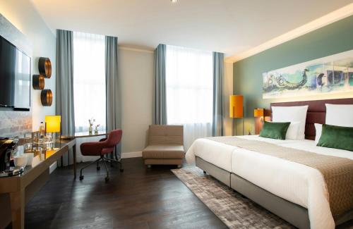 a hotel room with a bed and a desk and a desk at Leonardo Royal Hotel Berlin Alexanderplatz in Berlin