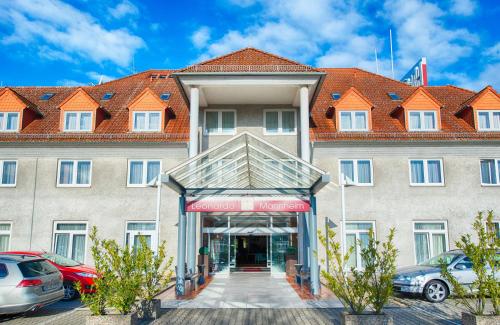 a large building with cars parked in front of it at Leonardo Hotel Mannheim-Ladenburg in Ladenburg
