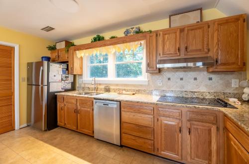 a kitchen with wooden cabinets and a refrigerator at Pappia - Duck, Sanderling, Oceanside, 150 Yards to Beach, on Lake, Community Pool in Duck
