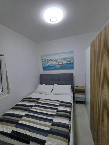 a bedroom with a bed with a striped blanket on it at Apartman Danijel in Bibinje