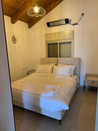 a bedroom with a large bed with white sheets at צימר בטבע in Majdal Shams
