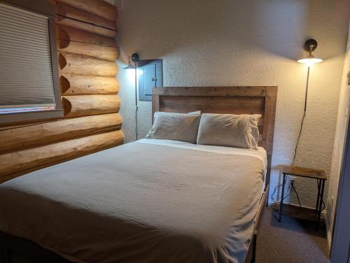 a bedroom with a bed and a wooden wall at Twin Peaks Hotel Cabins in Valemount