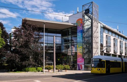 a yellow bus parked in front of a building at NYX Hotel Berlin Köpenick by Leonardo Hotels in Berlin