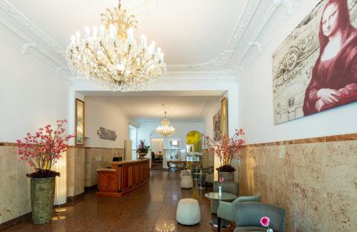 a lobby with a chandelier and chairs and a table at Leonardo Hotel Berlin KU'DAMM in Berlin