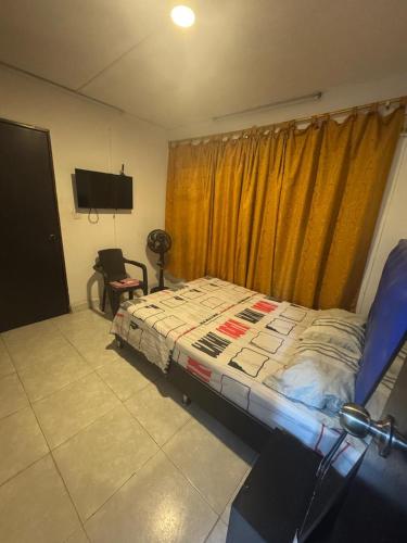 ein Schlafzimmer mit Bett, Fernseher und Fenster in der Unterkunft Casa Osiris in Cali