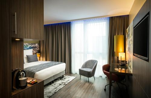 a hotel room with a bed and a chair at Leonardo Hotel Eschborn Frankfurt in Eschborn