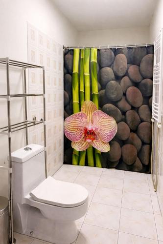 a bathroom with a toilet and a flower shower curtain at Gudauri Deka House, Balcony & Mountain Views in Gudauri