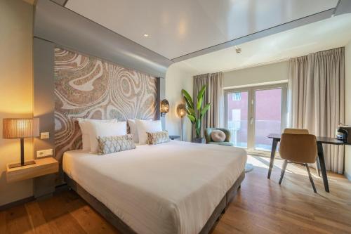 a bedroom with a large bed and a desk at Leonardo Hotel Breda City Center in Breda