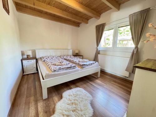 a bedroom with a white bed and a large window at Wellness chata Kozička in Klokočov