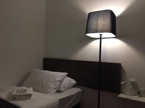 a bedroom with a bed with a lamp next to it at Lima.Tujoh in Kuching