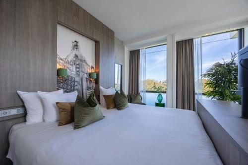 a large white bed in a room with windows at Leonardo Hotel Amsterdam Rembrandtpark in Amsterdam