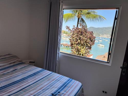 a bedroom with a window with a view of the ocean at Casa do Abrahão in Angra dos Reis