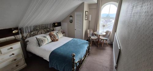 a bedroom with a bed and a table and a window at Denehurst Guest House - Adults Only in Windermere