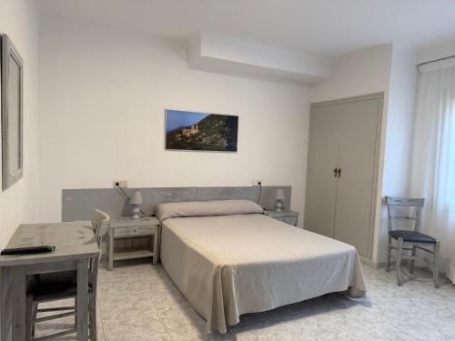 a bedroom with a bed and a table and a desk at Hotel Beri in Llança