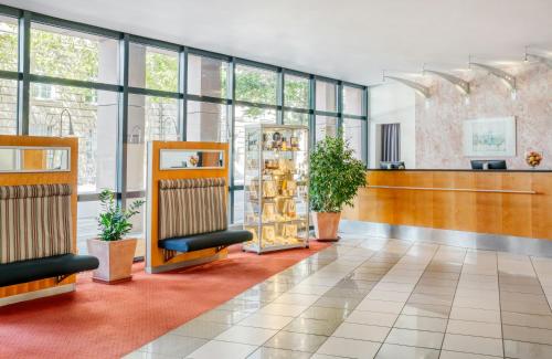 a lobby with chairs and plants in a building at Hotel Erfurt City Center by Leonardo Hotels in Erfurt