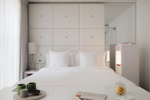 a white bedroom with a large white bed with a mirror at Leonardo Boutique Hotel Maastricht City Center in Maastricht